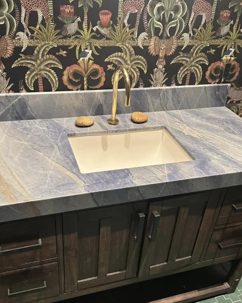 Brass gooseneck bathroom faucet on a blue stone vanity with an undermount sink