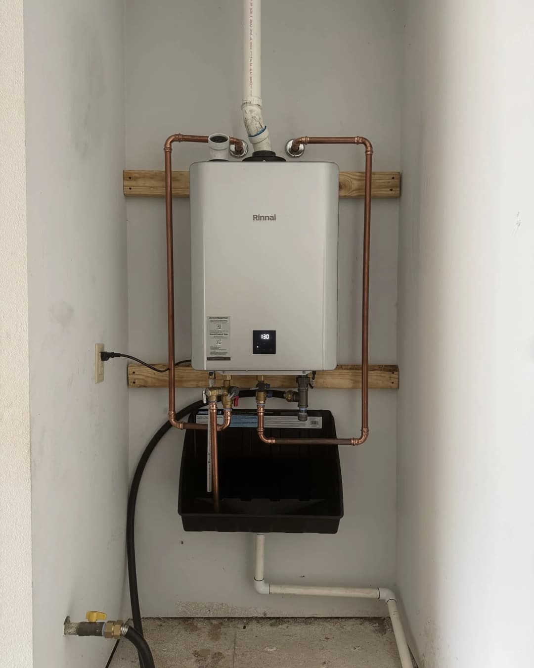 A wall-mounted Rinnai tankless water heater with new copper water lines