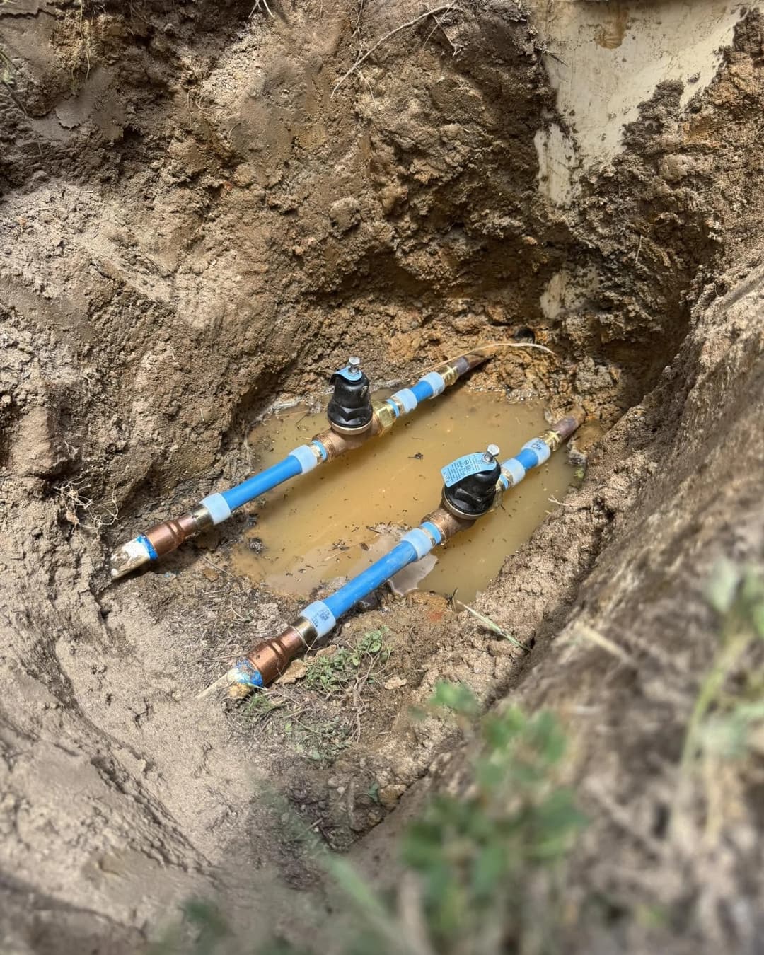New blue water service line and two water meters in an open trench