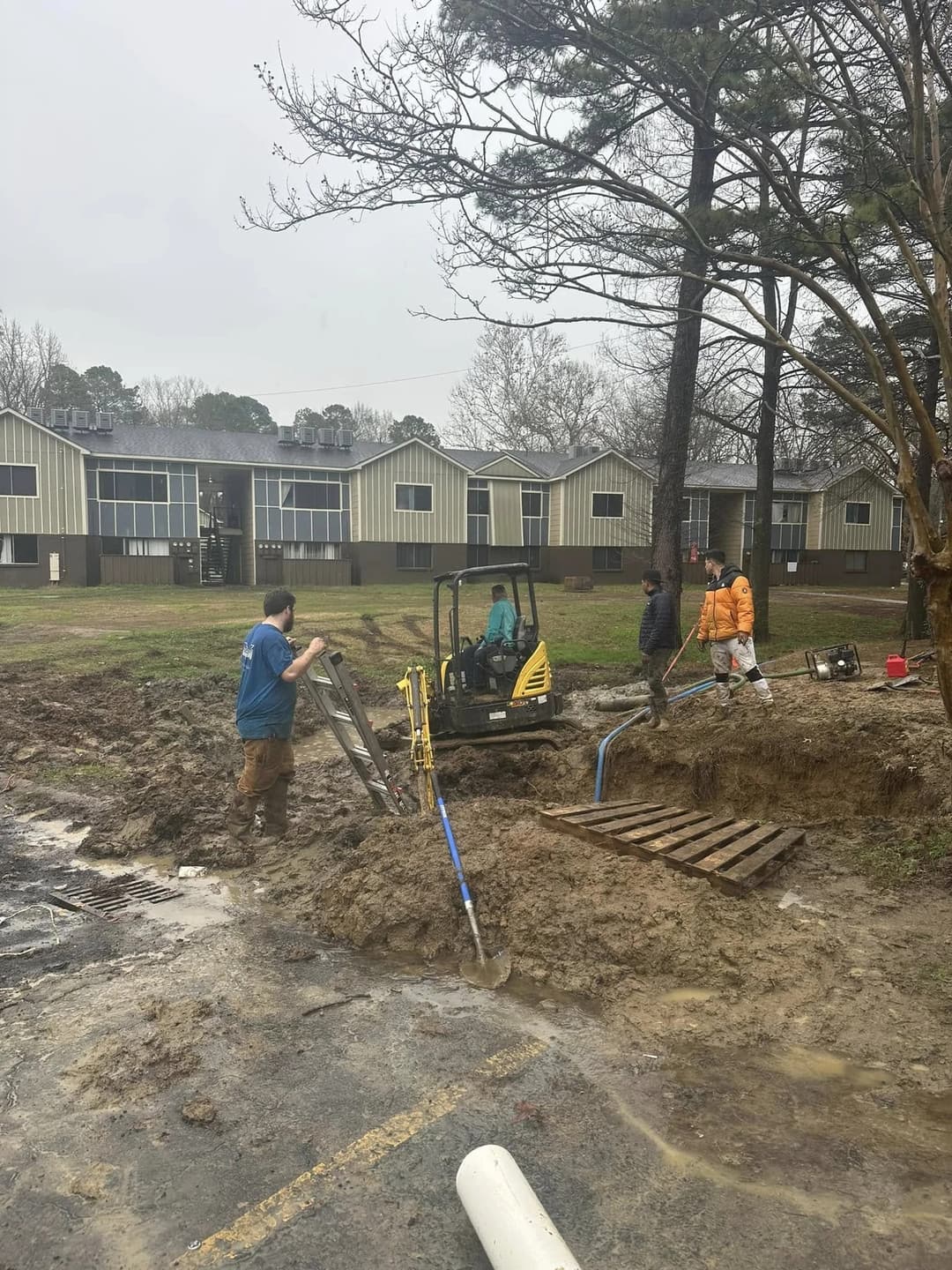 Victory Plumbing crew and mini excavator opening a water line at an apartment complex