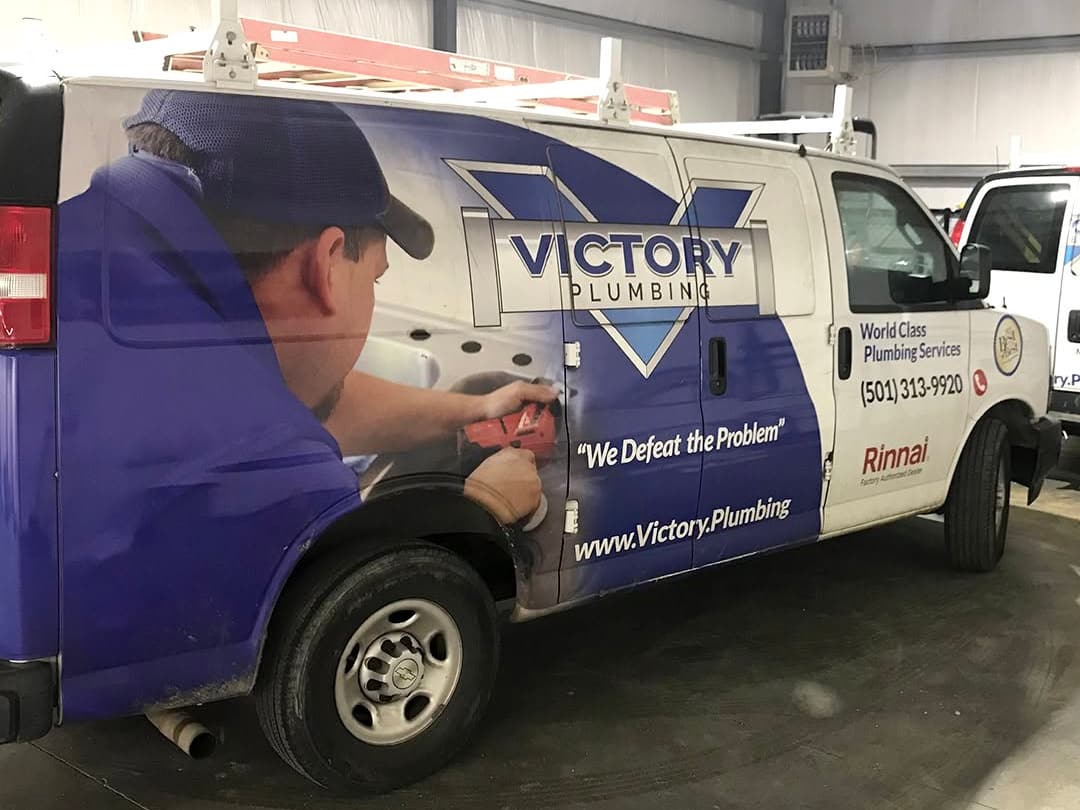 Victory Plumbing van parked inside the shop, with the Victory logo and service wrap visible.