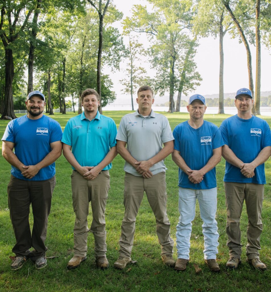 The Victory Plumbing team standing in a grassy area with trees in the background.